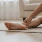 Osoba rukom pridržava petu bosog stopala zbog boli koju uzrokuje petni trn.
